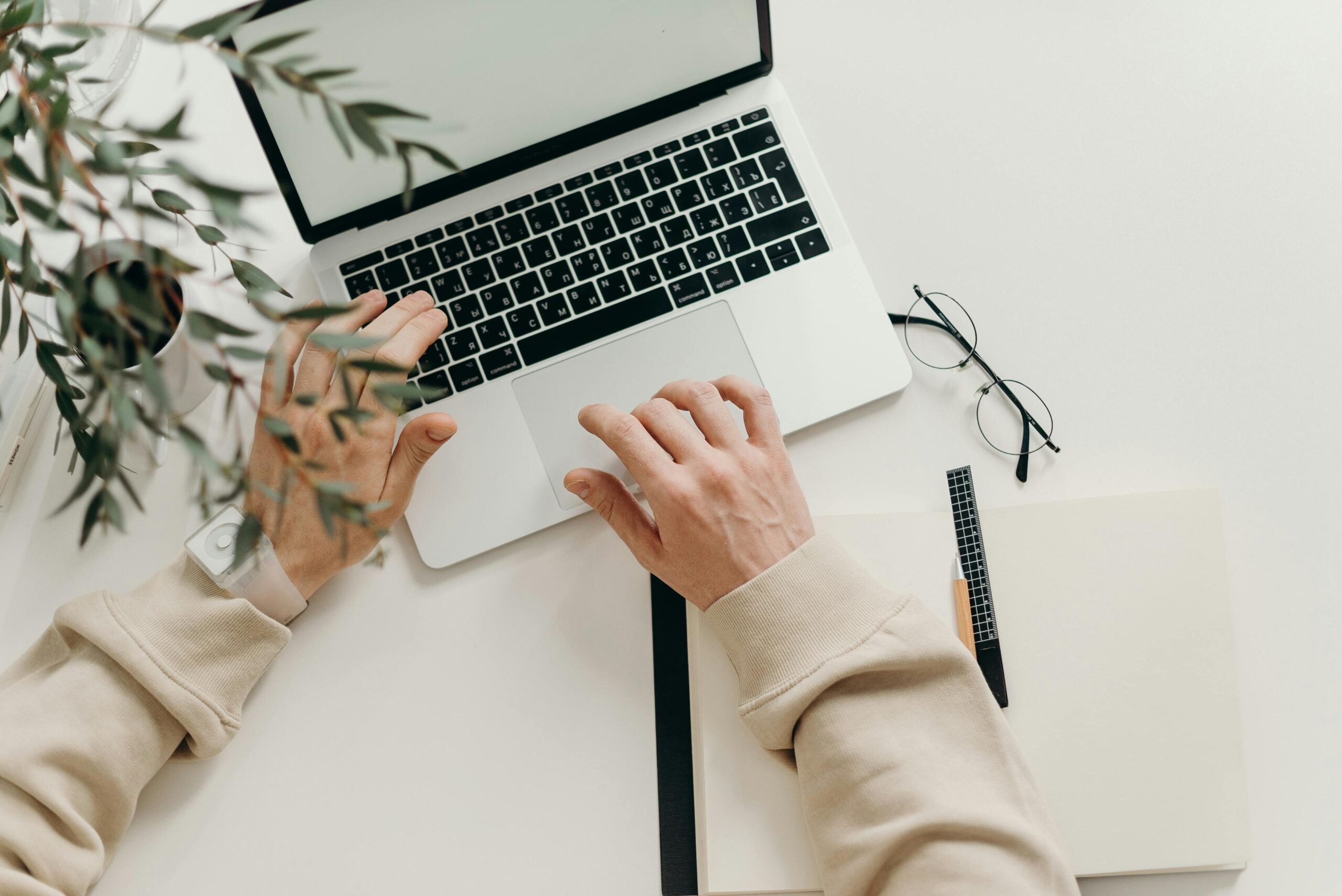 Free An overhead view of a person working on a laptop in a minimalist home office setting. Stock Photo