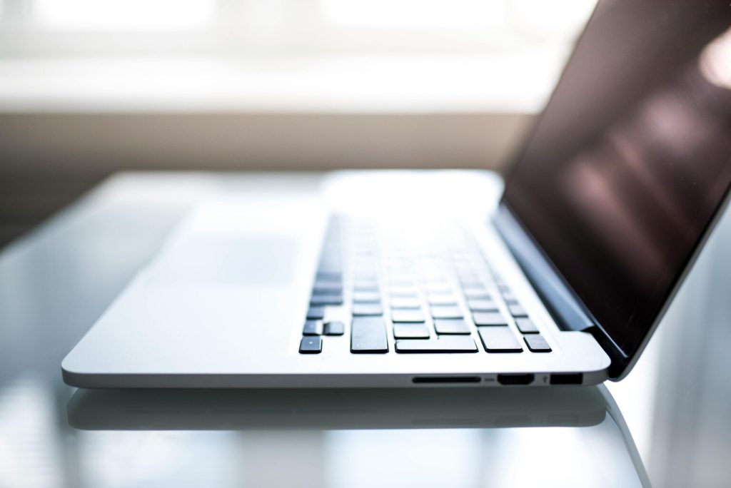 Free Elegant side view of a laptop on a glossy table with natural lighting indoors. Stock Photo